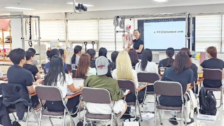 매직바디 강의실에서 강사가 화면을 띄워 놓고 교육생들에게 이론을 설명하는 모습